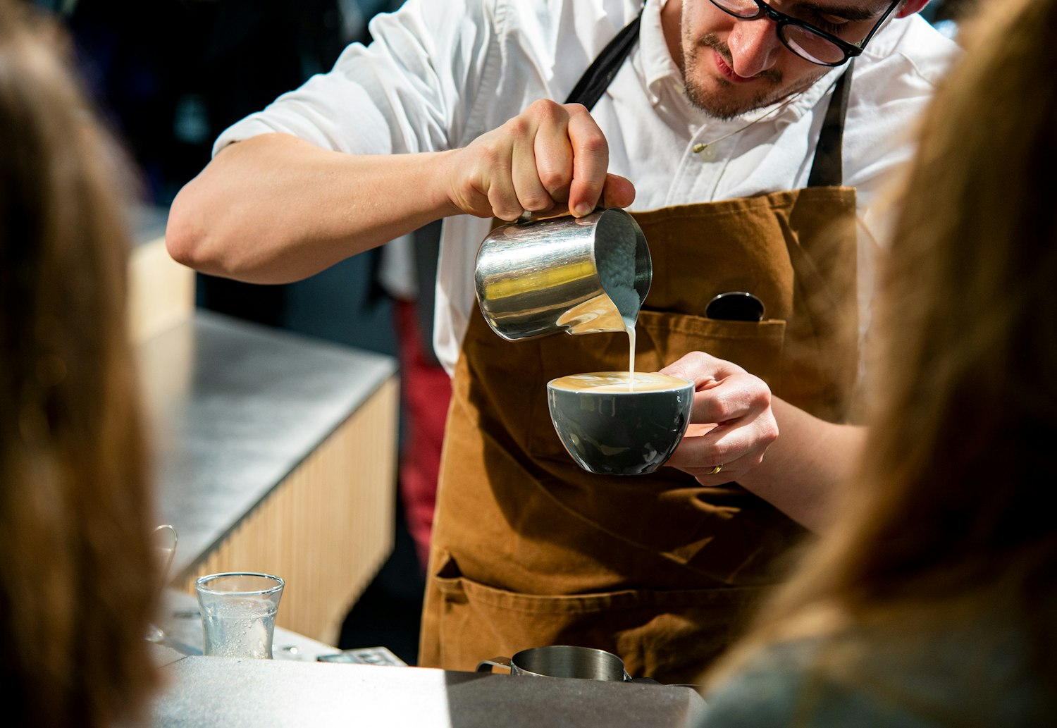 Barista sirviendo leche texturizada durante una capacitación